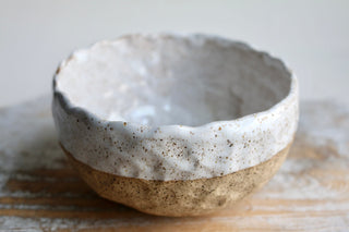a white and brown bowl sitting on top of a wooden table