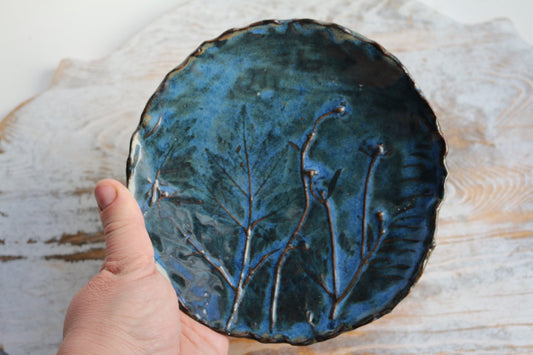 a hand is holding a blue plate with flowers on it