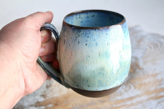 a hand holding a blue and white coffee cup