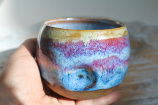 a hand holding a cup with a colorful design on it