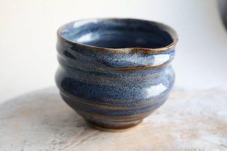 a close up of a blue vase on a table