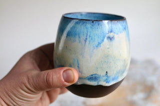 a hand holding a blue and white cup