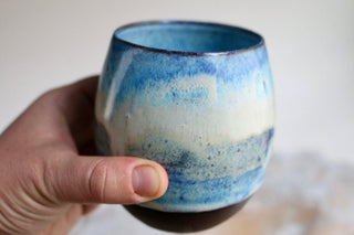 a hand holding a blue and white cup