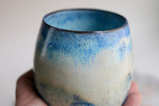 a hand holding a blue and white cup