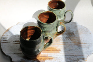 three coffee mugs sitting on top of a wooden table