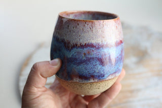 a hand holding a cup with a purple and blue design on it