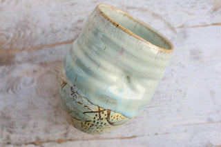 a ceramic cup sitting on top of a wooden table