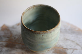 a green vase sitting on top of a table