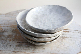 a stack of white plates sitting on top of a wooden table