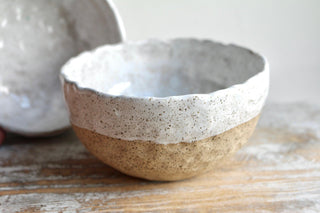 a white and brown bowl sitting on top of a wooden table