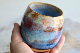 a hand holding a blue and brown cup