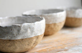 three white and brown bowls sitting on top of a wooden table