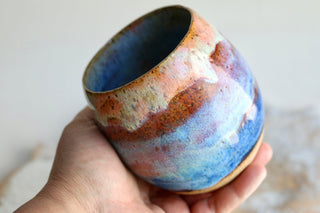 a hand holding a blue and brown cup