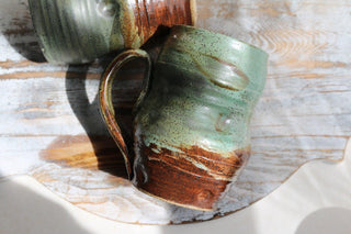 a couple of mugs sitting on top of a wooden table