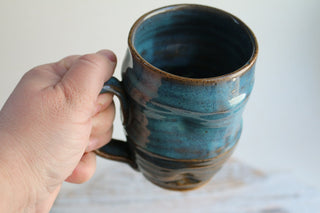a hand is holding a coffee mug in front of a white wall