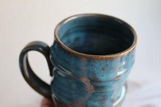 a hand holding a blue coffee mug on a table