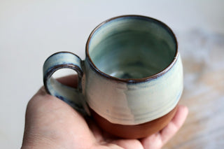 a hand holding a cup with a handle